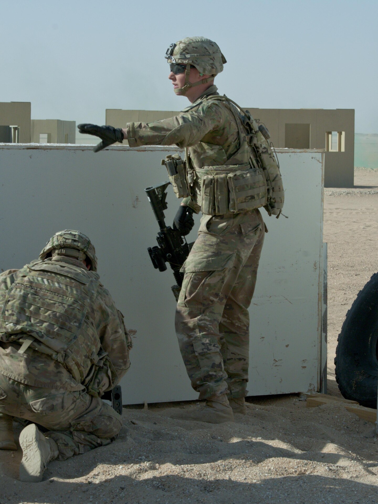 One soldier signals to another with hand gestures.