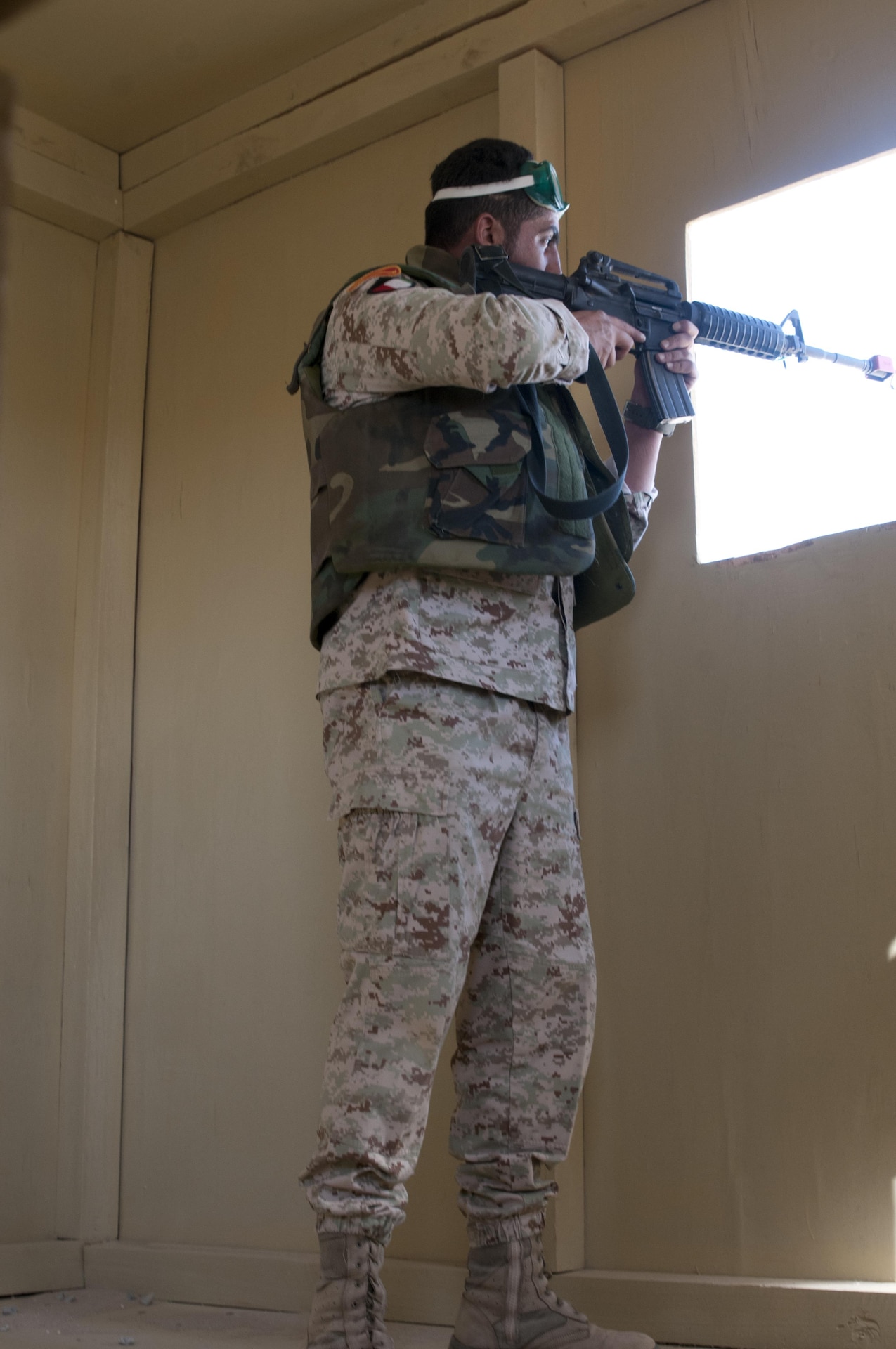 Soldier aims weapon out a window.