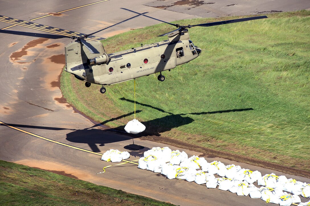 A CH-47 Chinook helicopter lifts large sand bags to be emplaces and fortify the spillway of the Guajataca Dam.