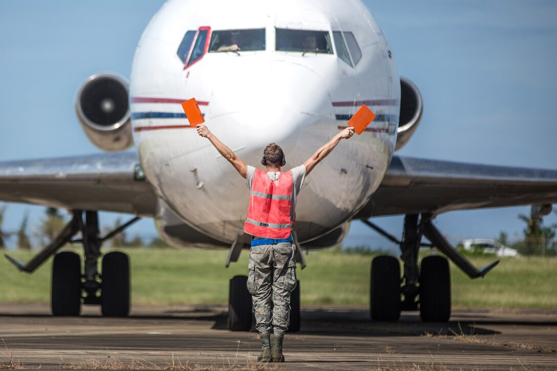 Senior Airmen Leo Anderson guides a 727 commercial airliner at Rafael Hernandez Airport.