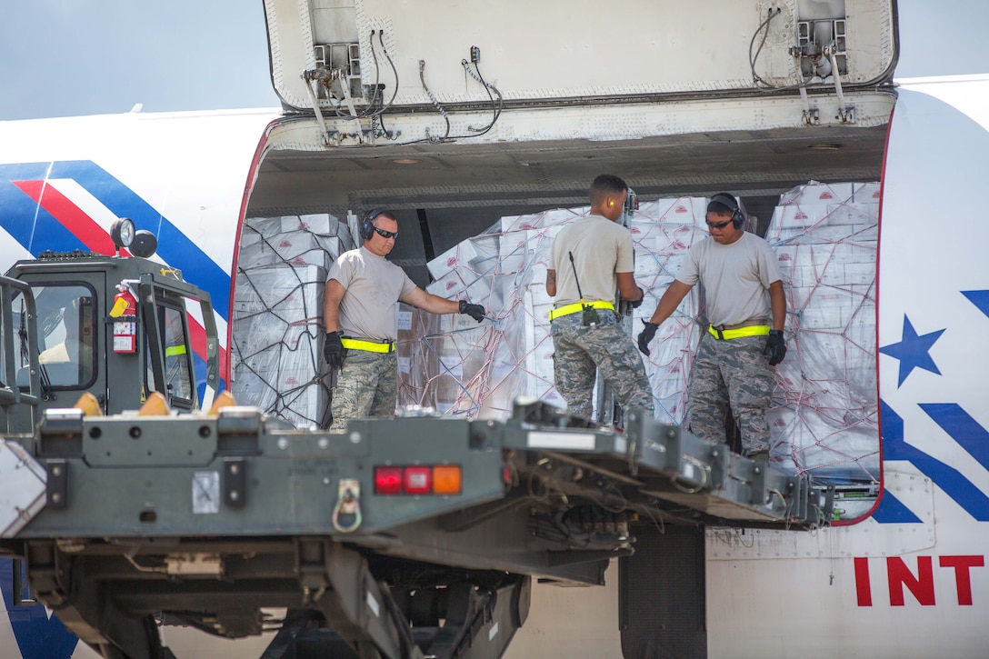 Airmen unload food, water and medical supplies off from a 727 commercial airliner.