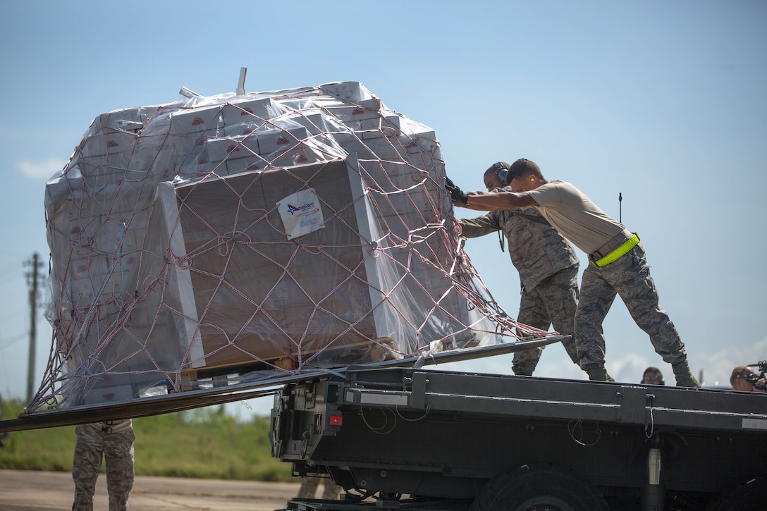 Airmen unload pallets of food from a 727 commercial airliner.