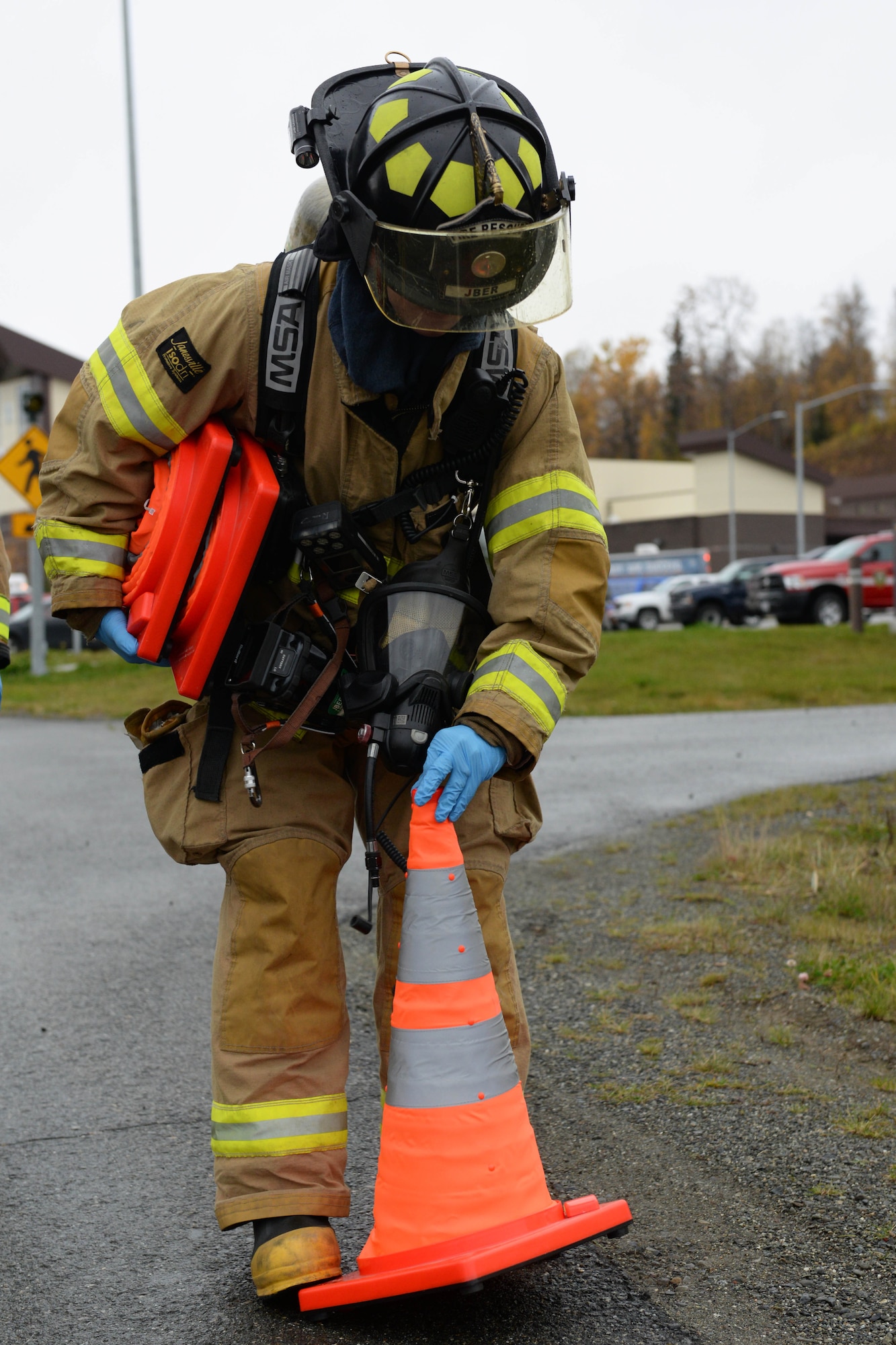 Senior Airman William White, fire protection specialist with the 673d Civil Engineer Squadron picks up a road cone during a fuel spill exercise Oct. 5, 2017, at Joint Base Elmendorf-Richardson, Alaska. White participated in a fuel spill exercise simulation, which tested the response actions of base recovery agencies in the event of a mass fuel spill, to ensure installation safety and minimal environmental impact.