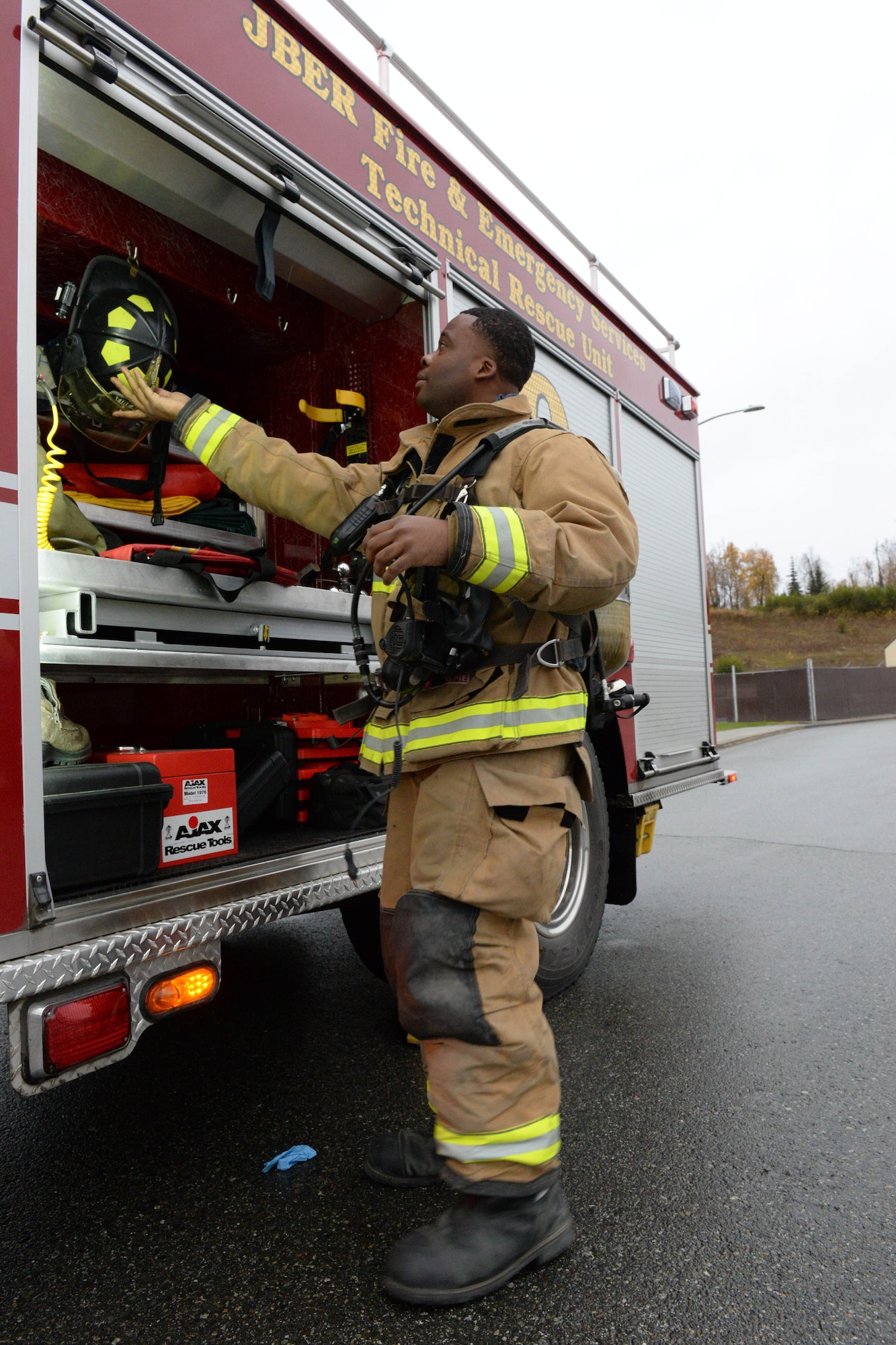 Senior Airman Cameron Nance, fire protection specialist with the 673d Civil Engineer Squadron, picks up gear from the fire truck Oct. 5, 2017, at Joint Base Elmendorf-Richardson, Alaska. Nance participated in a fuel spill exercise simulation, which tested the response actions of base recovery agencies in the event of a mass fuel spill, to ensure installation safety and minimal environmental impact.