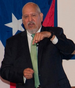 IMAGE: DAHLGREN, Va. (Sept. 28, 2017) - Hispanic Heritage Observance keynote speaker Lance Carrington encourages his audience to pray for the residents of Puerto Rico after Hurricane Maria devastated the island, and to pray for those living in Texas, the Gulf Coast, and Florida who are recovering from Hurricanes Harvey and Irma. Carrington – retired from the Senior Executive Service (SES) as a special agent for NASA and the U.S. Postal Service – recounted his life and career which included service in the Army as a reserve chief warrant officer. He retired from the Army reserves on Oct. 1, 2017 after more than 35 years of active duty, National Guard, and reserve service. He is currently executive director of the Catholic Diocese of Arlington’s Guadalupe Free Clinic in Colonial Beach, Va. The clinic serves the indigent and medically-uninsured population in Westmoreland County and Colonial Beach, on the Northern Neck of Virginia.