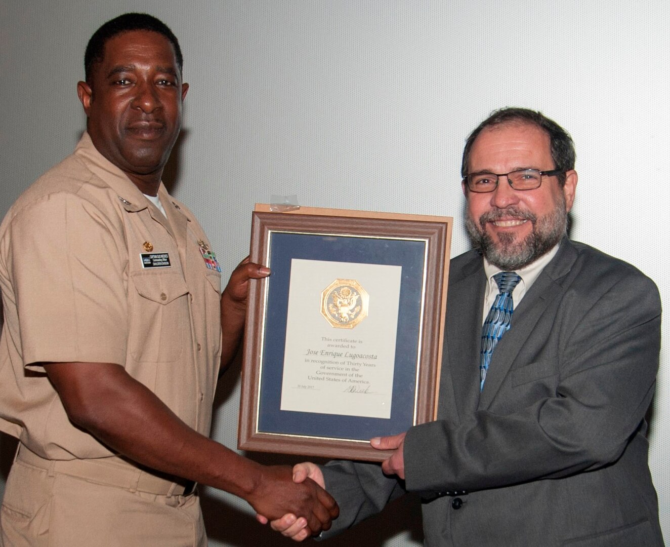 IMAGE: DAHLGREN, Va. (Sept. 28, 2017) - Naval Surface Warfare Center Dahlgren Division (NSWCDD) Commanding Officer Capt. Godfrey 'Gus' Weekes presents NSWCDD senior engineer Jose Lugo with a certificate recognizing Lugo's 30 years of government service before military, government civilians, and defense contractors celebrating Hispanic Heritage Month at the Naval Support Facility Dahlgren theater. "As we celebrate this Heritage Month, I want you all to remember that in order to shape the bright future of America, each one of us has to be a point of light," Lugo told the audience after receiving his certificate. "We have to brighten the day of everybody around us and we have to inspire those who follow us, and in doing so we will improve our future."  At this year's event, personnel from NSF Dahlgren and tenant commands gathered at the base theater to join the Navy and nation while celebrating and reflecting on the theme "Shaping the Bright Future of America."