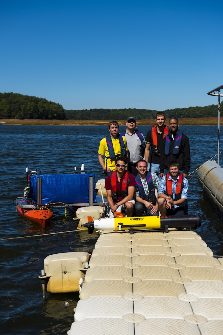 Engineers from Naval Surface Warfare Center, Carderock Division launch an unmanned surface vehicle in Triadelphia Reservoir near Brighton Dam in Brookville, Md., that will function as a relay for an unmanned underwater vehicle conducting bathymetry in the reservoir Sept. 28, 2017. Staff from the Naval Meteorological and Oceanography Command controlled the collaborative autonomous demonstration via satellite connection from their headquarters at John C. Stennis Space Center in Mississippi with assistance from the Autonomous Vehicle and Instrumentation Group and other Carderock personnel. Rear row, left to right: electrical engineer Woody Pfitsch (Code 863), program officer Judah Milgram (Code 882), hardware engineer Alex Punzi (Code 863), group leader Jim Rice (Code 8633); front row, left to right: electrical engineer Ben Gordon (Code 8633), control systems engineer Matt Greytak (Code 861) and mechanical engineer Kyle Corfman (Code 863). (U.S. Navy photo by Ryan Hanyok/Released)