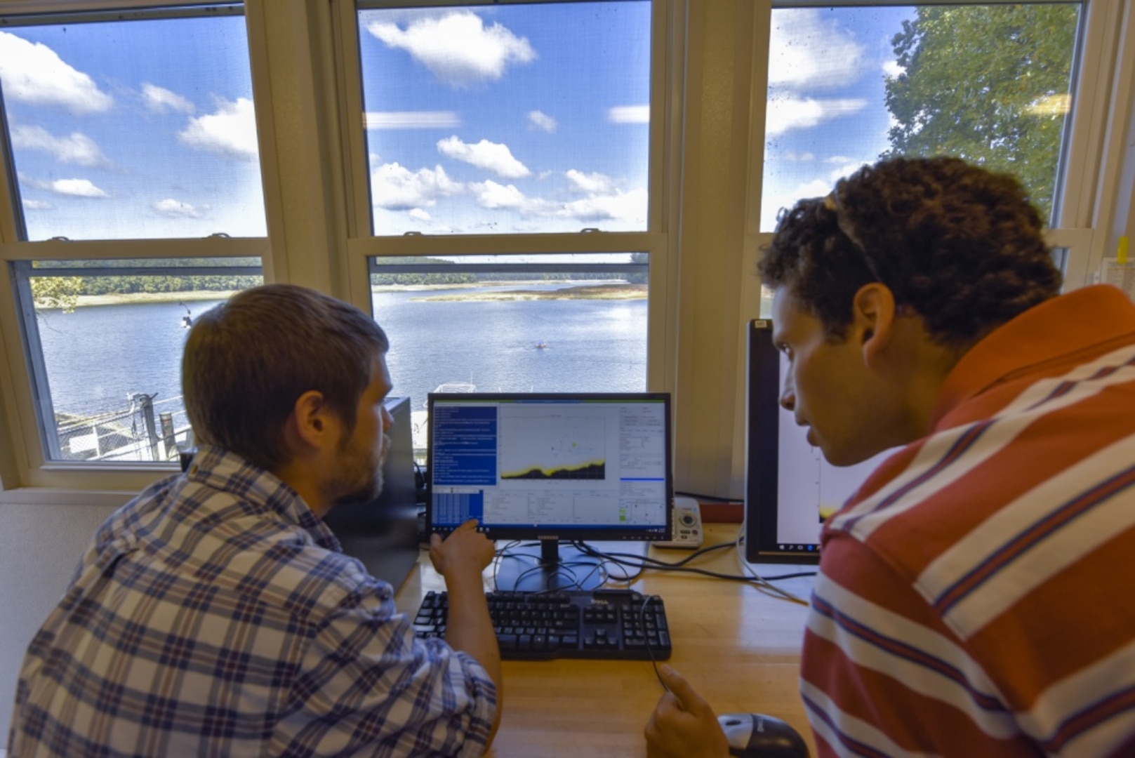 Ben Gordon and Kyle Coffman, engineers assigned to Naval Surface Warfare Center, Carderock Division™s Autonomous Vehicle and Instrumentation Group, supervise a joint integrated autonomous demonstration being run remotely by colleagues from the Naval Oceanographic Office at the John C. Stennis Space Center in Mississippi from the control room at the Triadelphia Reservoir in Brookeville, Md., Sept. 27, 2017. (U.S. Navy photo by Harry Friedman/Released)