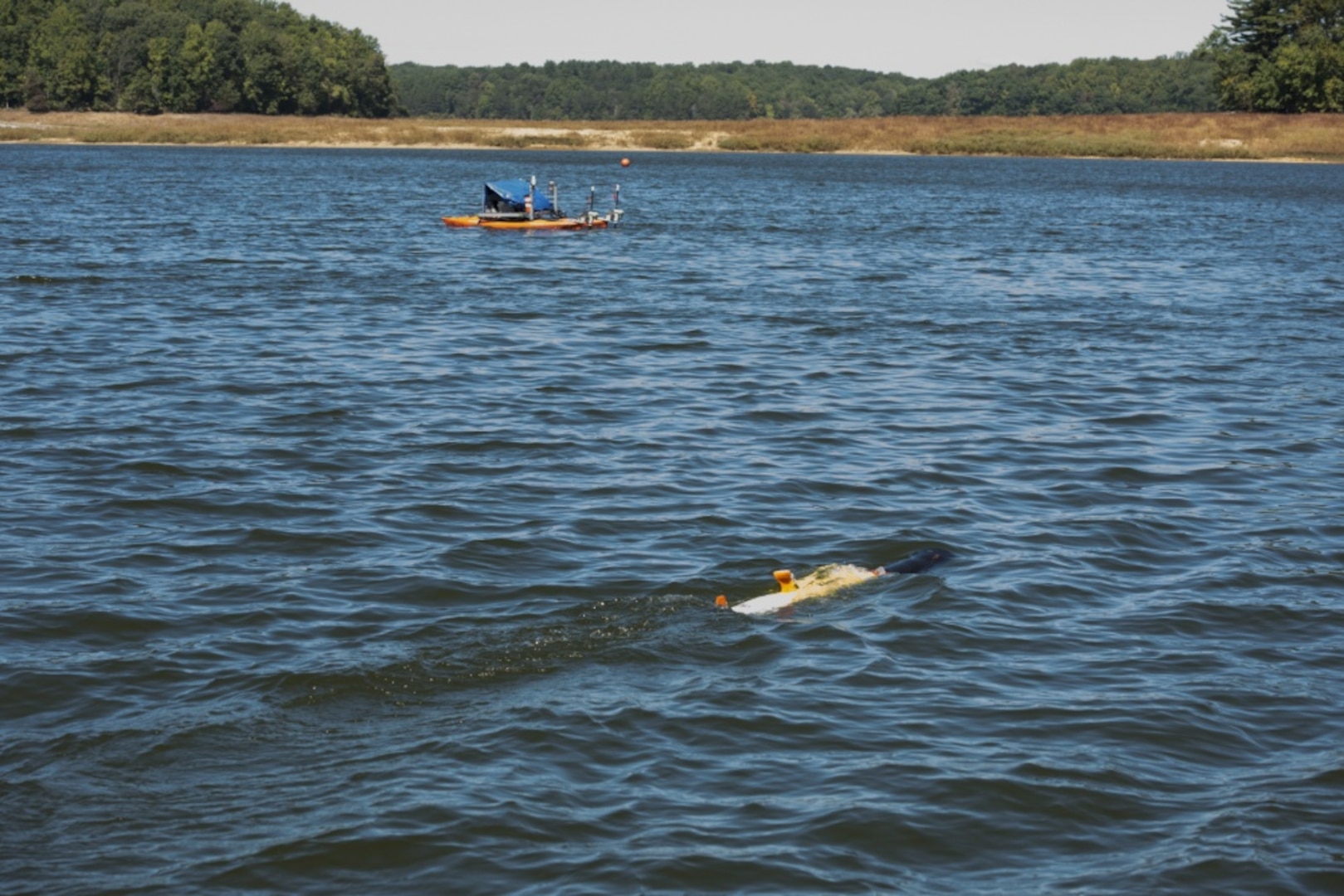 A kayak catamaran unmanned surface vehicle follows an unmanned underwater vehicle in Triadelphia Reservoir in Brookeville, Md., Sept. 28, 2017, during a joint integrated autonomous demonstration with engineers from the Naval Oceanographic Office at the John C. Stennis Space Center in Mississippi controlling the test with supervision and assistance from colleagues on station from Naval Surface Warfare Center, Carderock Division™s Autonomous Vehicle and Instrumentation Group. (U.S. Navy photo by Ryan Hanyok/Released)