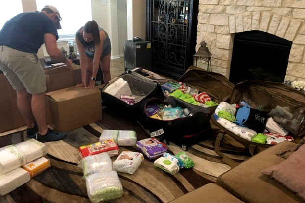 Two people box piles of supplies stacked on the floor.