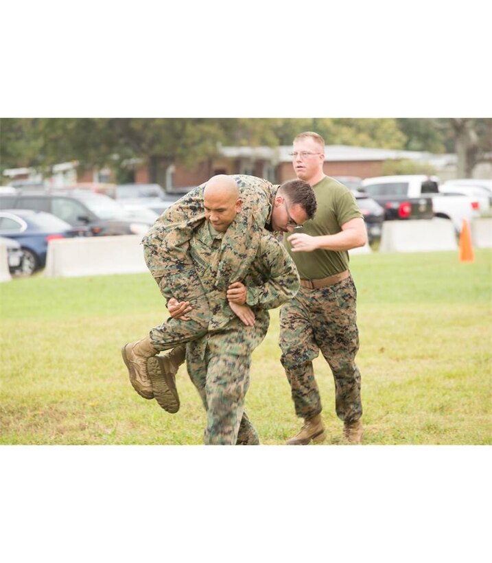 Master Sgt. Nephtali Ricafrente, air traffic control operations specialist, U.S. Marine Corps Forces Command Headquarters, fireman-carries Lance Cpl. Jordan Clark, Marine Air Ground Task Force planner, MARFORCOM, during the "maneuver under fire" event of the Combat Fitness Test at the Headquarters and Service Battalion building, Norfolk, Va., Oct. 11. The CFT is conducted annually and consists of three events designed to test a Marine's strength, muscular
endurance, and cardiovascular capabilities. (Official Marine Corps photo by Chris Jones/Released)
