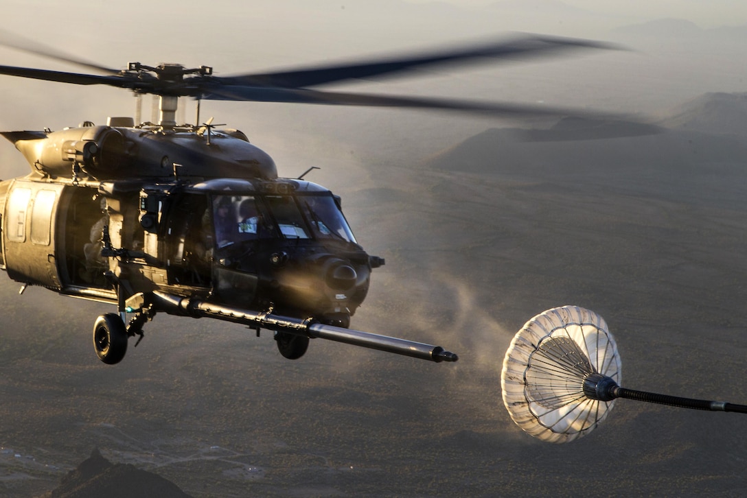 A helicopter approaches a refueling aircraft.