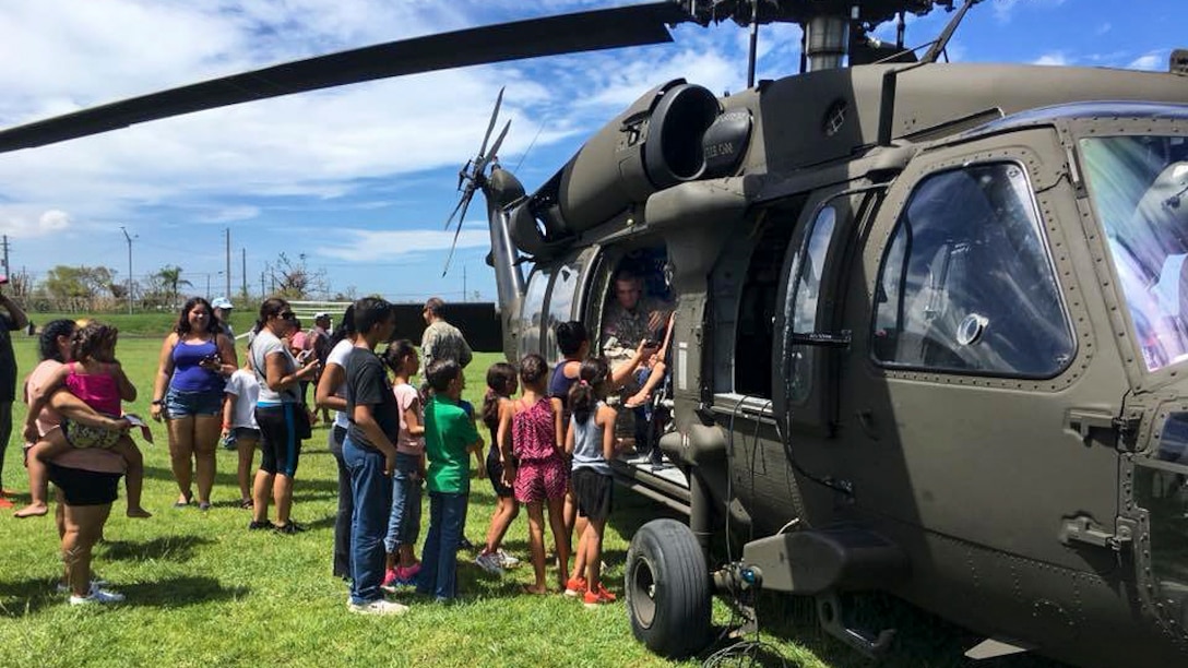 Soldiers and residents unload relief supplies from a helicopter.