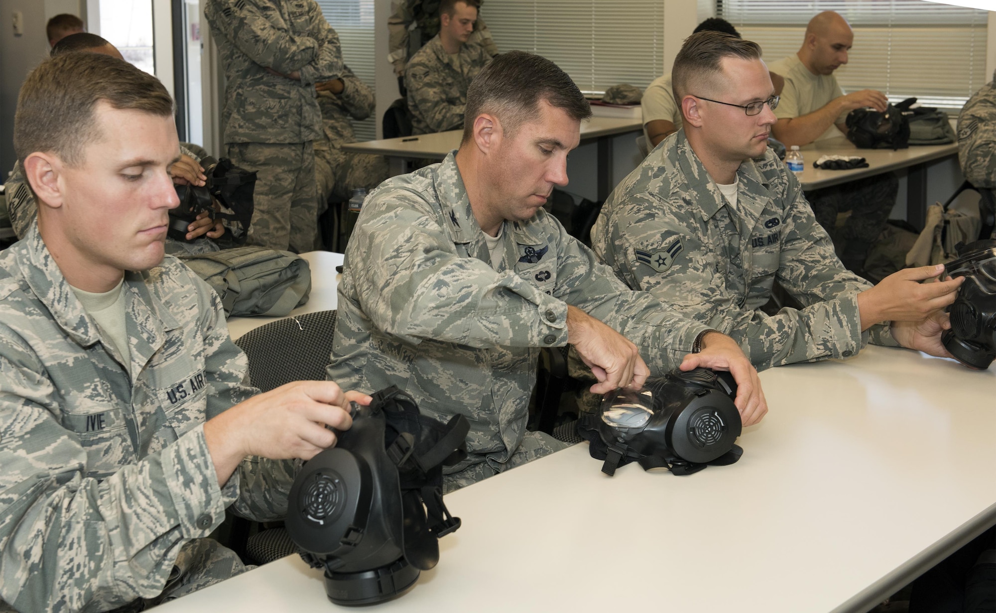 U.S. Air Force Senior Airman Cody Ivie (left), 921st Contingency Response Squadron, U.S. Air Force Col. John Klein (left), the commanding officer of the 60th Air Mobility Wing, and Senior Airman Alexander Valks (right), 660th Aircraft Maintenance Squadron, inspect their gas masks during a chemical, biological, radiological and nuclear defense survival skills training course on Travis Air Force Base, Calif., Sep. 21, 2017. The course consists of individual and team demonstration performance objectives that provide hands-on training and evaluation of knowledge acquired. (U.S. Air Force photo by Heide Couch)