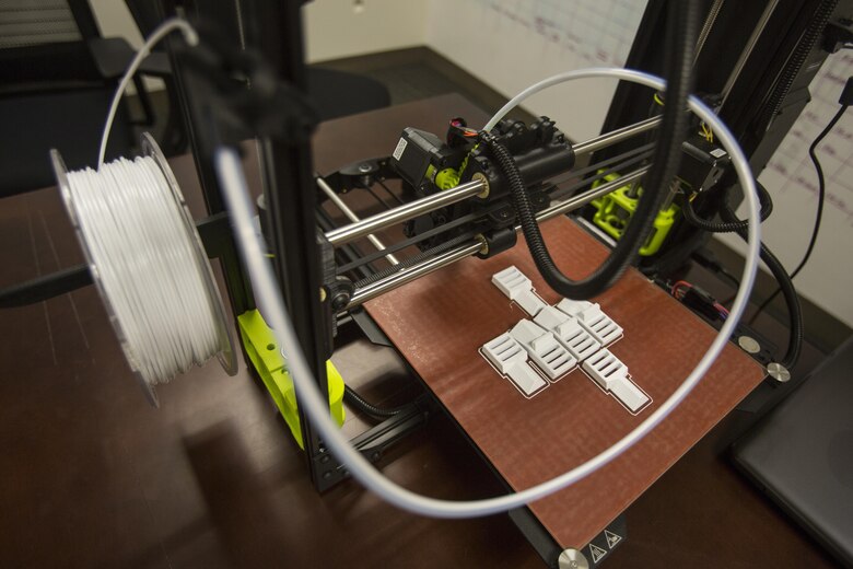 The 3-D printer and the finished layout of pack clips from 2nd Battalion, 8th Marine Regiment at Camp Lejeune, N.C., Oct. 6, 2017. 2/8 is the first infantry battalion in the United States Marine Corps to utilize a 3-D printer to ensure battalion readiness in the event of equipment malfunctions. (U.S. Marine Corps photo by Lance Cpl. Ashley McLaughlin)