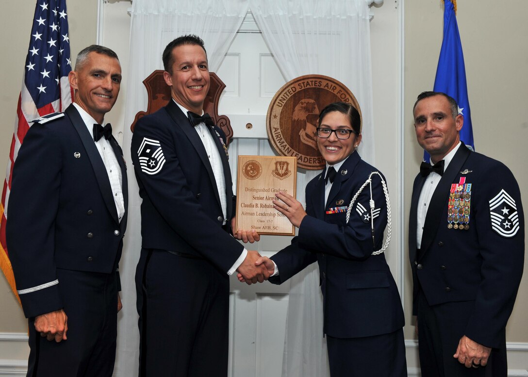 U.S. Air Force Senior Airman Claudia Robaina-Santiago, 3rd Intelligence Squadron, receives a Distinguished Graduate Award from Senior Master Sgt. Keith Rivers of the Shaw Diamond Council, during the Senior Master Sgt. David B. Reid Airman Leadership School Class 17-7 graduation ceremony at Shaw Air Force Base, S.C., Oct. 6, 2017.