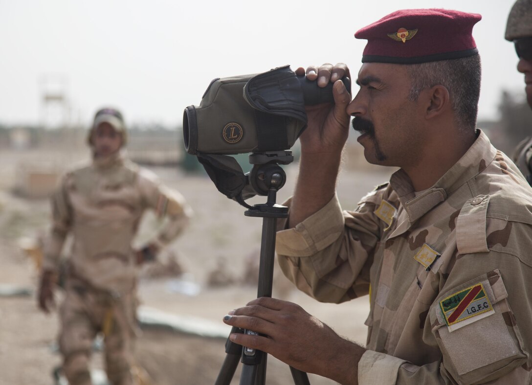 A member of the Iraqi security forces looks at a target while directing a fellow trainer in marksmanship training at Camp Taji, Iraq.