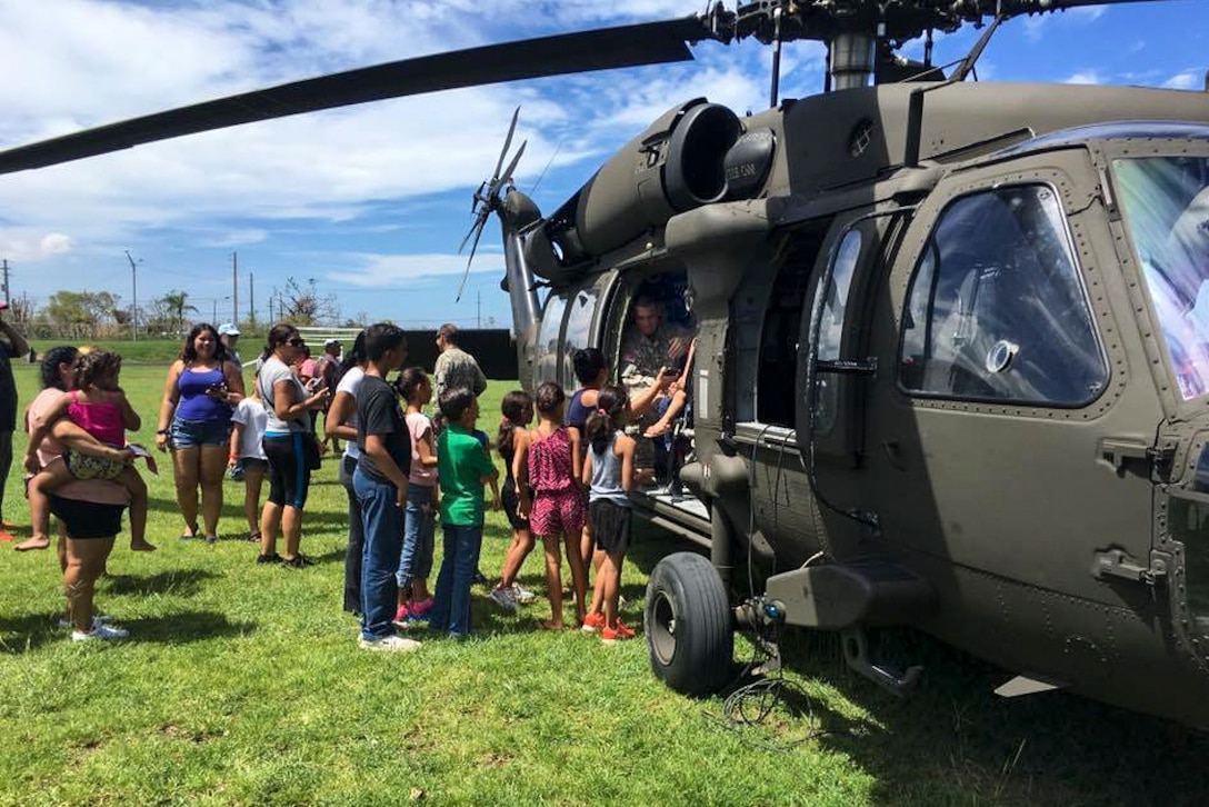 Soldiers and residents unload relief supplies from a helicopter.