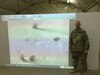 Solider stands in front of projection screen.