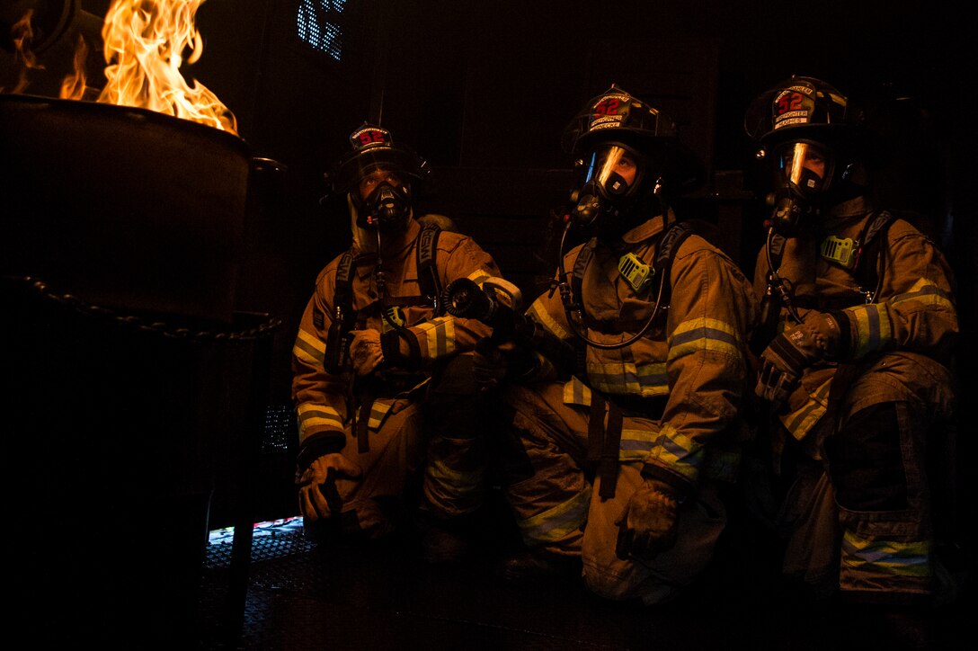 Senior Airman Robert Jones, left, Airman 1st Class Nicholas Jarnecke, center, and Airman 1st Class Tyler Jones, right, all 52nd Civil Engineer Squadron firefighters, experience a rollover fire inside a burn house trailer at Spangdahlem Air Base, Germany, Oct. 5, 2017. Rollover fires happen when fire gasses rise in an enclosed area, collect on the ceiling and ignite. (U.S. Air Force photo by Senior Airman Preston Cherry)