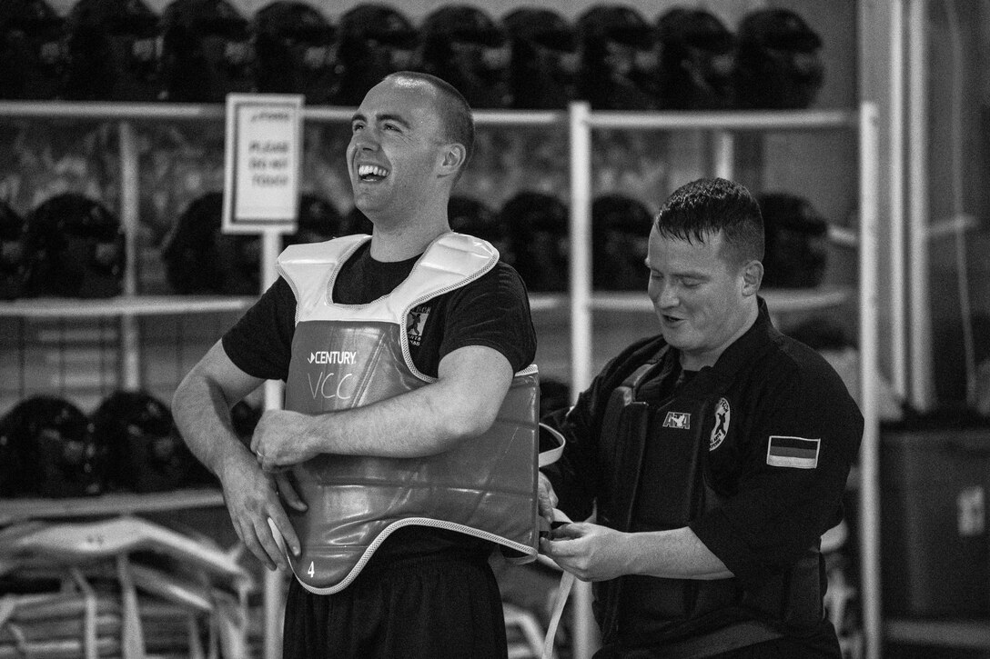 U.S. Air Force Staff Sgt. Brandon Sabin, 86th Airlift Wing Public Affairs broadcast journalist, laughs with U.S. Army Staff Sgt. Michael Decker, during a mixed martial arts class at the Vogelweh Community Center on Vogelweh Military Complex, Germany, Oct. 11, 2017. Sabin sparred against five people in a row in order to receive his black belt. (U.S. Air Force photo by Senior Airman Devin Boyer)