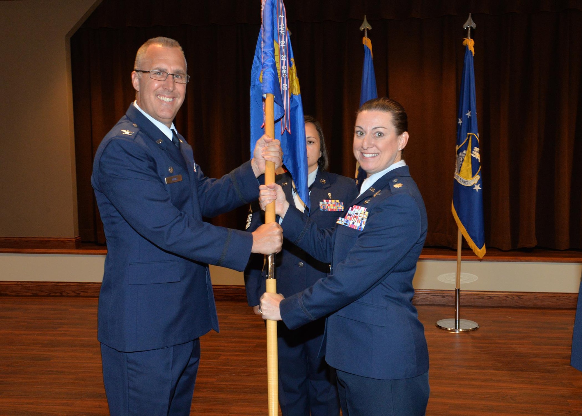 Col. Rick Johns, (Left) 88th Communications Group commander passes the 88th Communications Squadron guidon to Lt. Col. Kelly West, 88th Communications Squadron commander, as she assumes her new post as the commander during the change of command ceremony at Wright-Patterson Air Force Base, July 17, 2017. West assumes command from outgoing Lt. Col. Brian Snyder as he departs for his new assignment at the Pentagon, Washington D.C. (U.S. Air Force Photo  by Al Bright/Released)