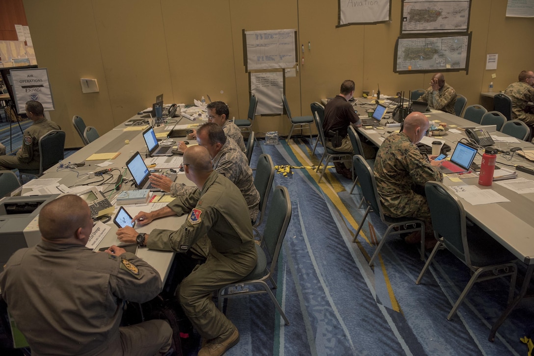 Airmen work with representatives of other agencies in a hurricane relief coordination center.