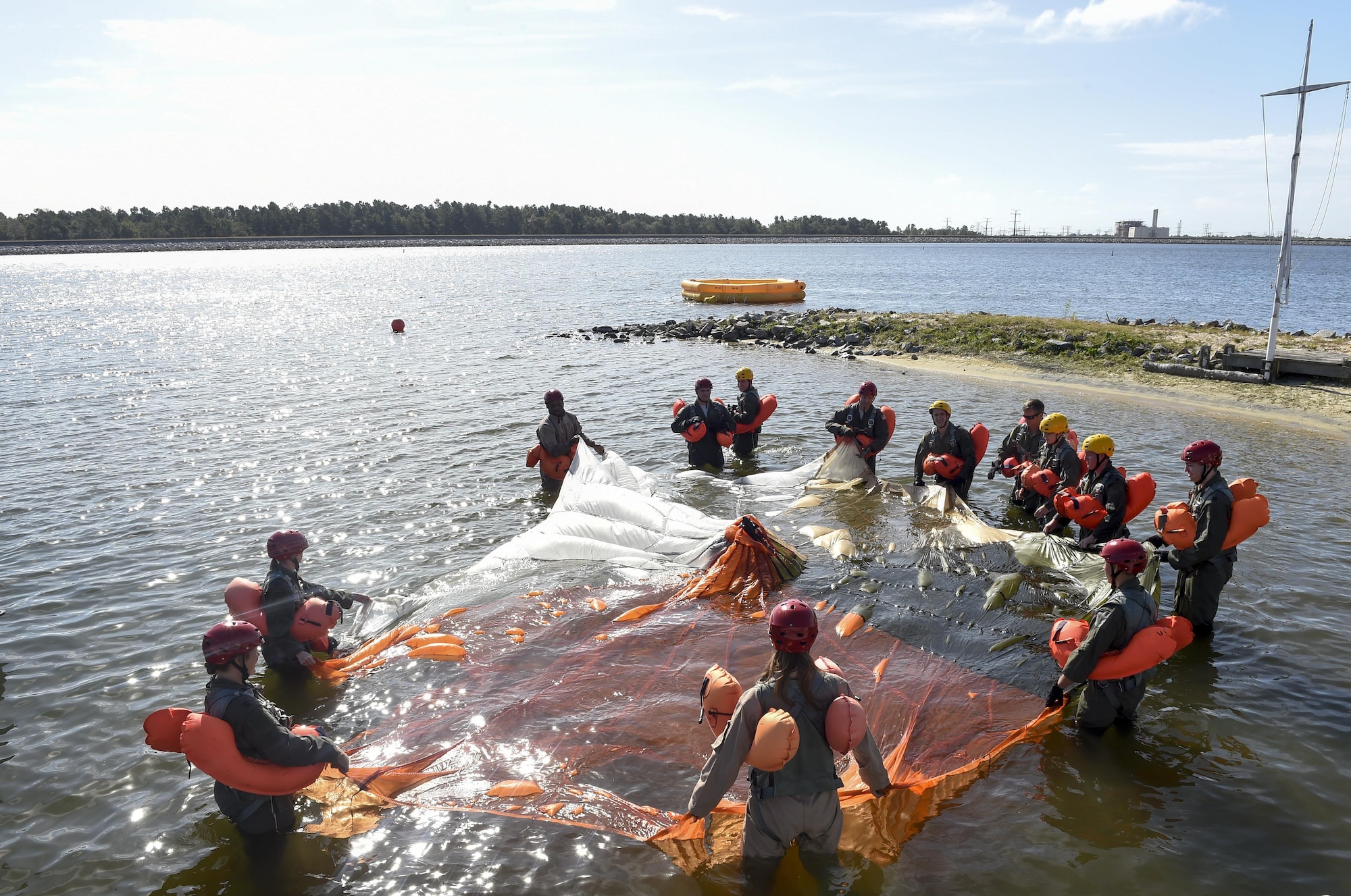 Students stretch out a parachute during Survival, Evasion, Resistance and Escape Block Training so while a fellow student uses water survival techniques to get out from under a parachute Oct. 2, 2017.