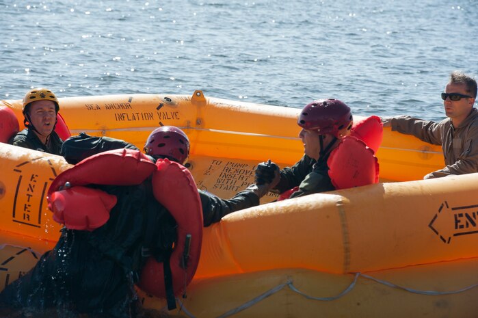Students work together to get into a life raft during Water Survival Training as Senior Airman Jerid Bauscher, 437th Operations squadron SERE Specialist, right, ensures they use proper technique Oct. 2, 2017.