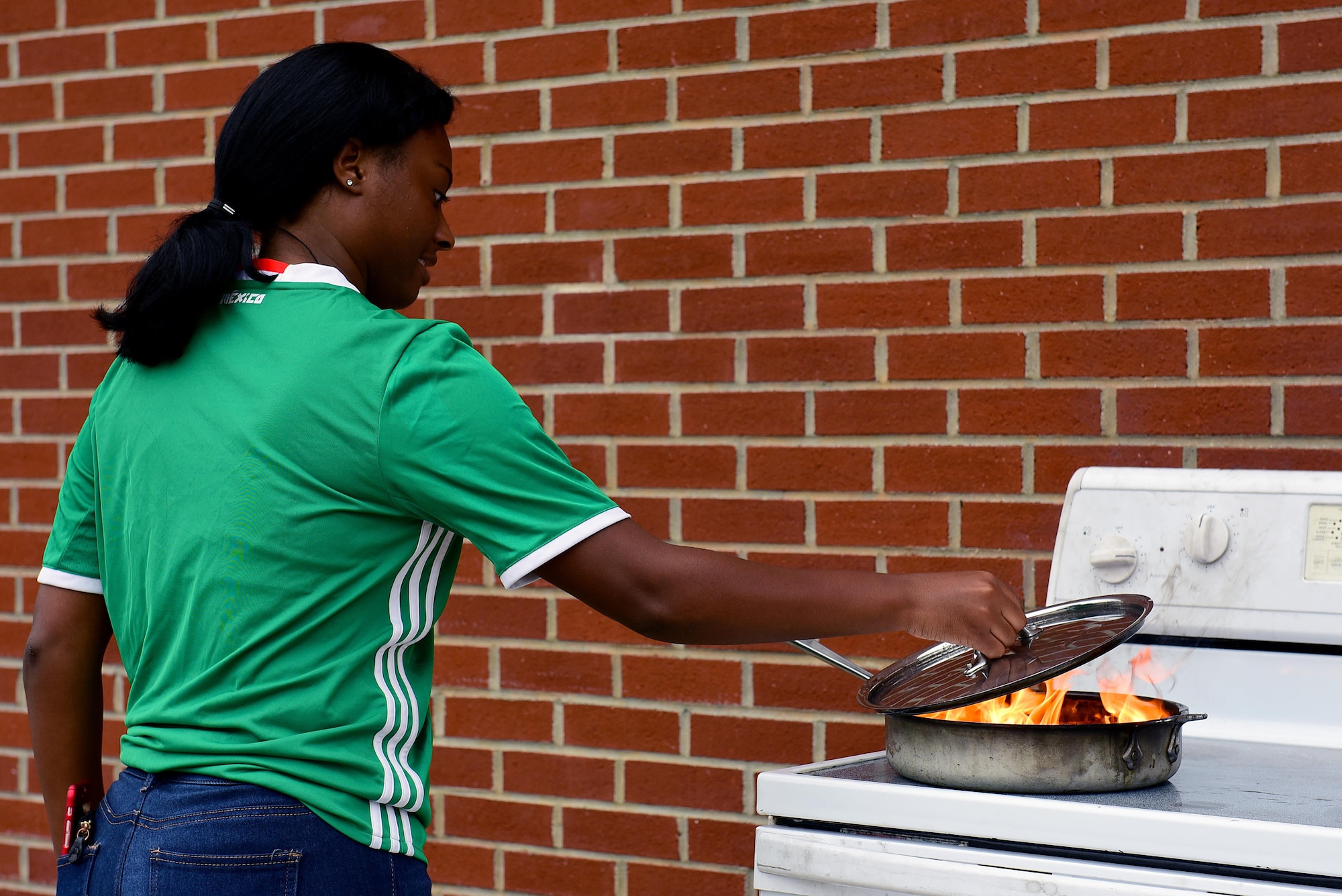 Dellnique Ballen puts out a grease fire during a demonstration at the Base Exchange parking lot for Fire Prevention Week, Oct. 13, 2017, at Seymour Johnson Air Force Base, North Carolina. According to the National Fire Protection Association, almost half of all reported home structure fires are caused by cooking. (U.S. Air Force photo by Airman 1st Class Kenneth Boyton)