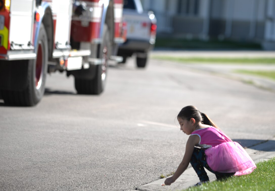 Emmalyn Jensen, daughter of Staff Sgt. Michael Jensen, a cyber transport systems technician assigned to the 28th Communications Squadron, picks up candy on the side of the road during the Fire Prevention Week Parade at Ellsworth Air Force Base, S.D., Oct. 7, 2017. Members of the Ellsworth community came out to participate in the parade and raise awareness for fire prevention. (U.S. Air Force photo by Airman 1st Class Thomas Karol)