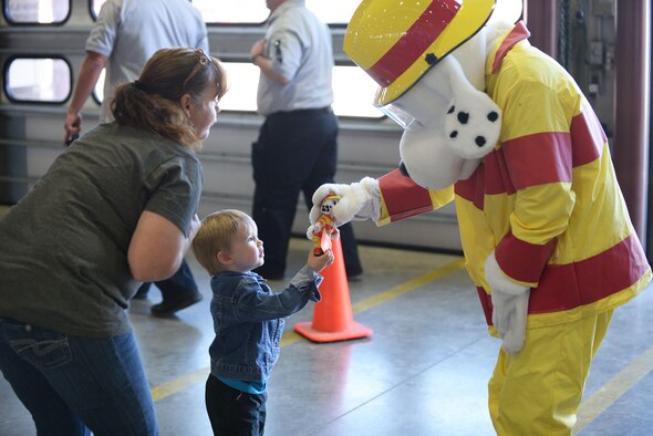 A child gives Sparky the Fire Dog, the mascot of the 28th Civil Engineer Squadron Fire Protection Flight, a toy identical to himself at Ellsworth Air Force Base, S.D., Oct. 7, 2017. The 28th CES Fire Protection Flight hosted an open house for the local community and kicked off National Fire Prevention Week by raising awareness about fire safety. (U.S. Air Force photo by Airman 1st Class Thomas Karol)