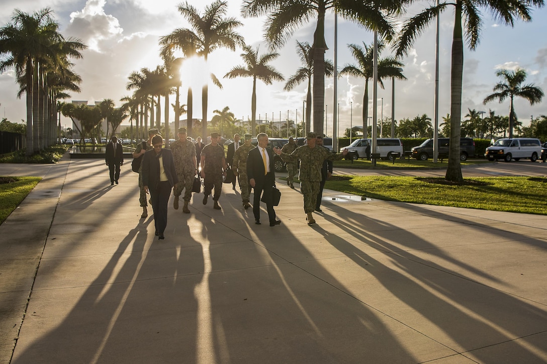 Defense Secretary Jim Mattis walks with leaders as light casts shadows.