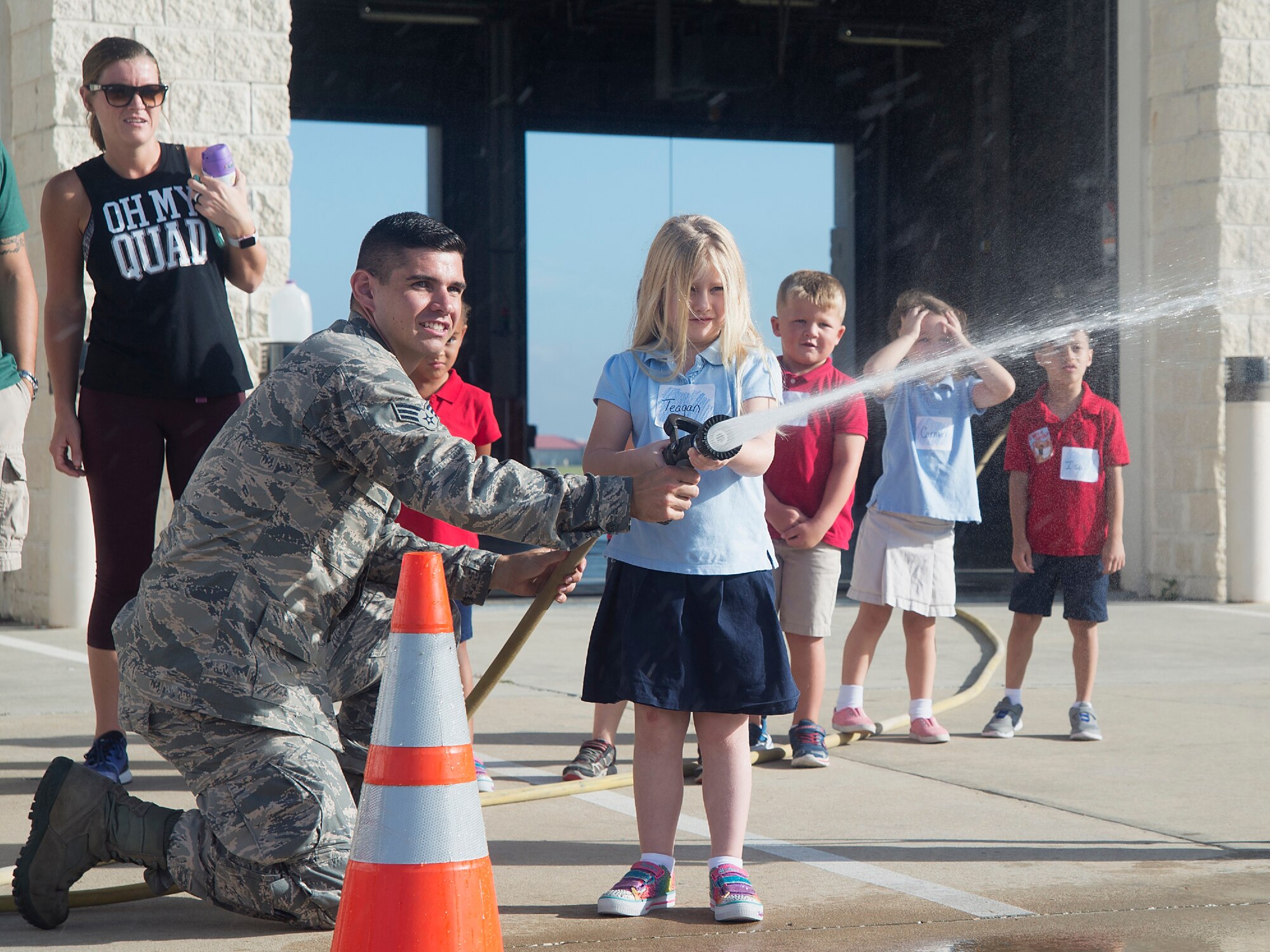 U.S. Air Force Senior Airman Jacob Holdgate, a firefighter assigned to the 6th Civil Engineer Squadron, helps a Tinker K-8 School student extinguish a makeshift fire at MacDill Air Force Base, Fla., Oct. 10, 2017.