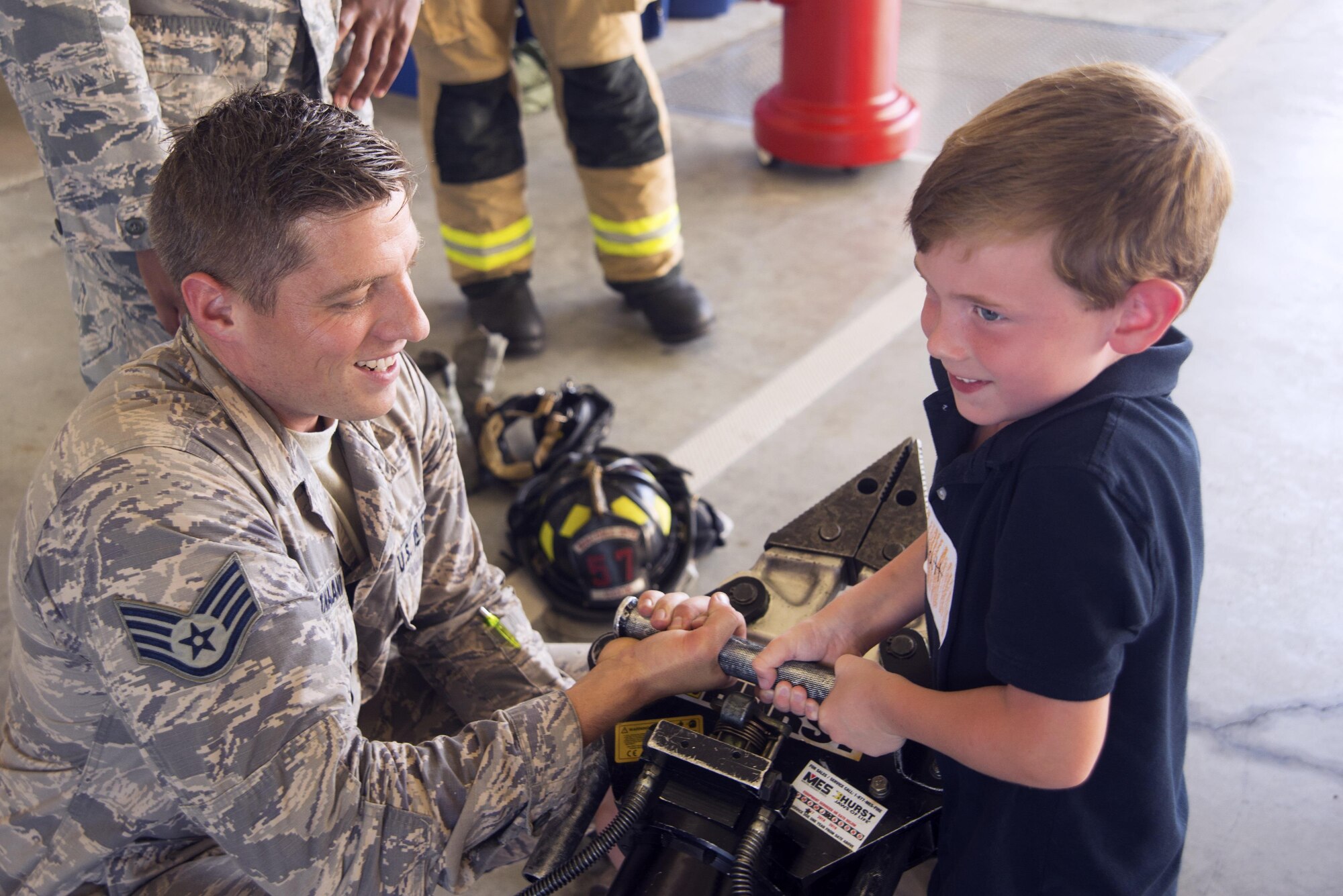 U.S. Air Force Staff Sgt. Casey Stanaland, a crew chief assigned to the 6th Civil Engineer Squadron, helps a Tinker K-8 School student lift a Hurst Rescue Tool at MacDill Air Force Base, Fla,. Oct. 10, 2017.