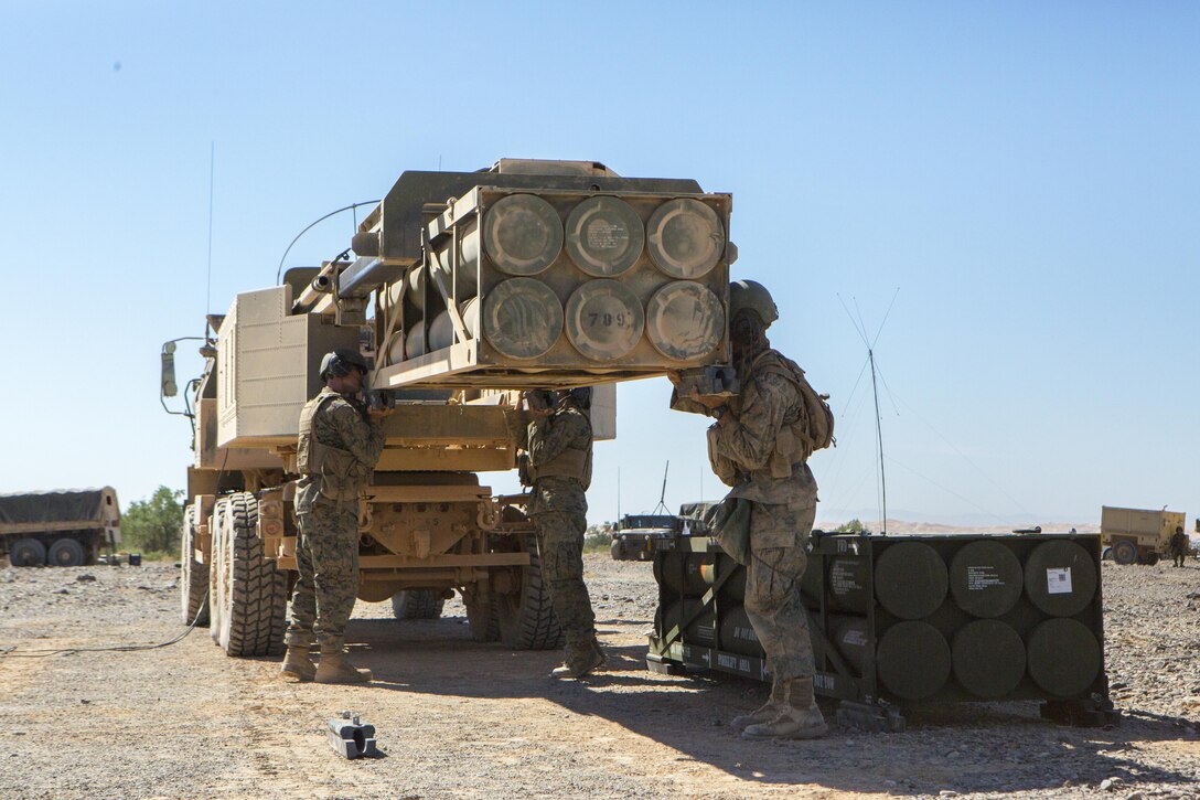 Sgt. Jansen Davis (left), a section chief with 3rd Platoon, Rocket Battery F, 2nd Battalion, 14th Marine Regiment, 4th Marine Division, Marine Forces Reserve, Lance Cpl. Zane Treece (center) and Lance Cpl. Justin Minor (right), a driver and gunner with 2/14, respectively, guide a trainer launch pod out of an M142 High Mobility Artillery Rocket System carrier during Weapons and Tactics Instructor course 1-18 at Landing Zone Bull Attack, near the Chocolate Mountain Aerial Gunnery Range, California, Oct. 11, 2017. The Marines with 2/14 are participating in WTI 1-18 to increase their proficiency with the HIMARS and to build experience with firing Guided Multiple Launch Rocket System munitions, thus advancing their combat effectiveness and readiness for future exercises and deployments. (U.S. Marine Corps photo by Cpl. Dallas Johnson/Released)