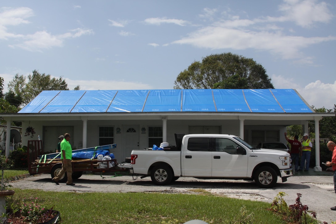 Contractors pack up materials and gear after installing fiber-reinforced plastic sheeting on a Hurricane Irma-damaged roof in Sebring, Florida Oct. 1, 2017