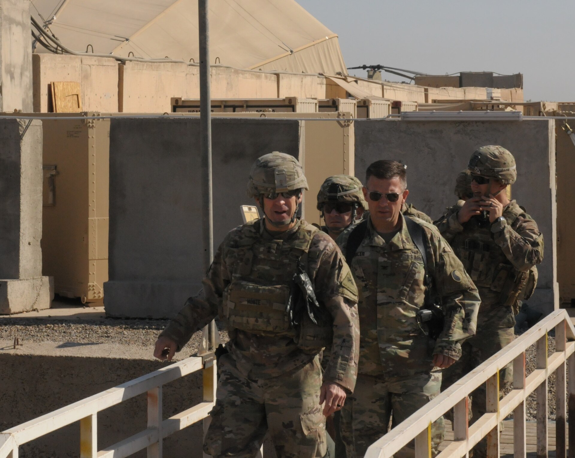 Soldiers walk across a small bridge.