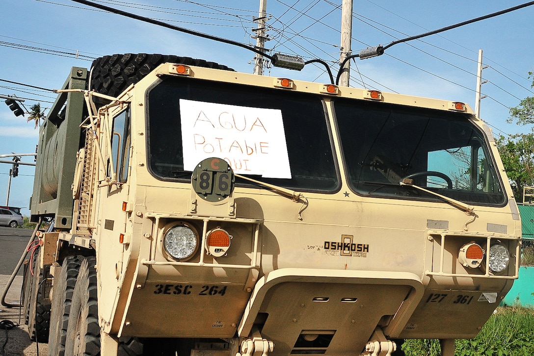 A military vehicle sits with a sign on the windshield.