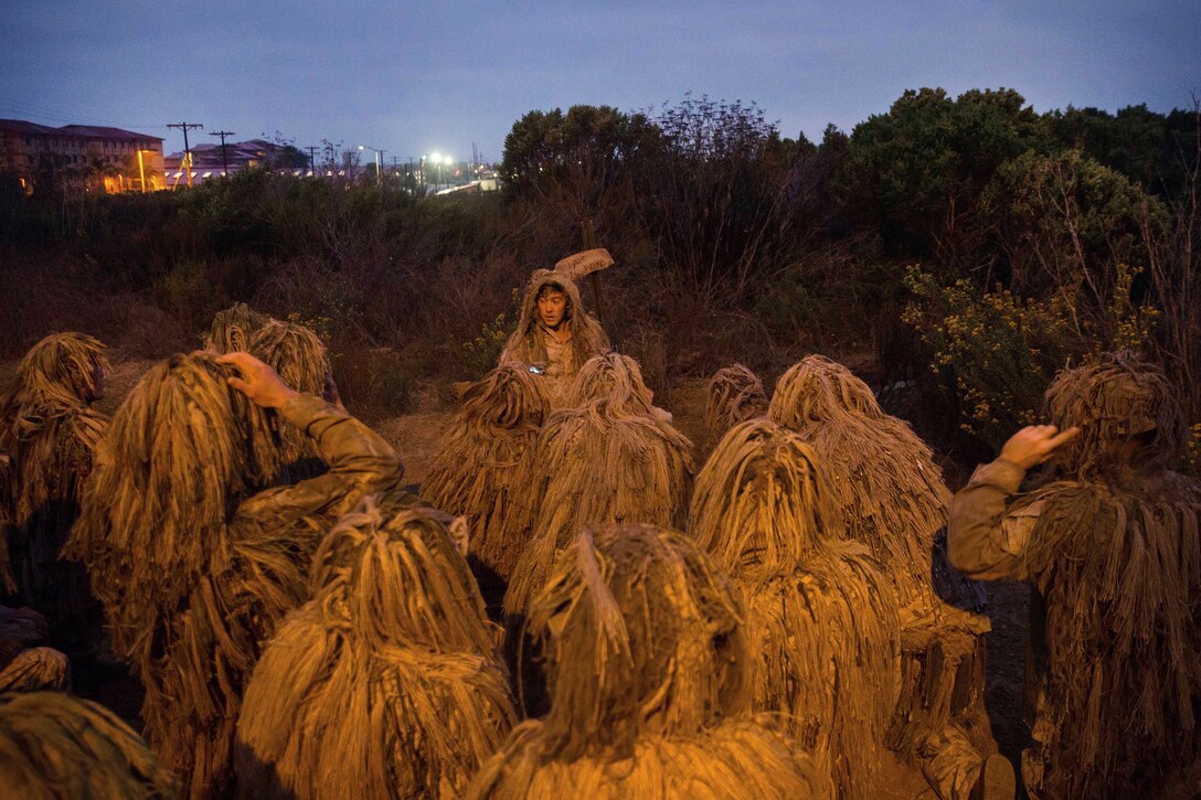 Marines in ghillie suits group together.