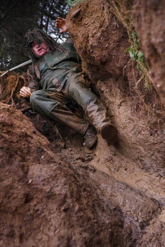 A Marine slides down a mud ramp.