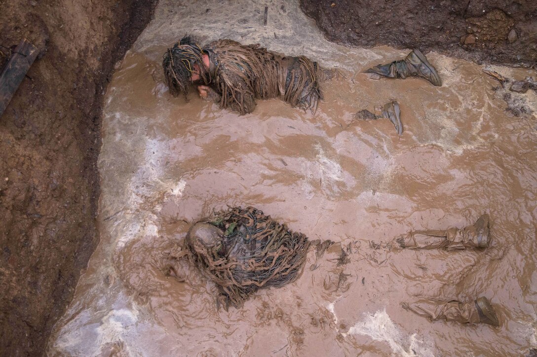 Marines lay in muddy water.