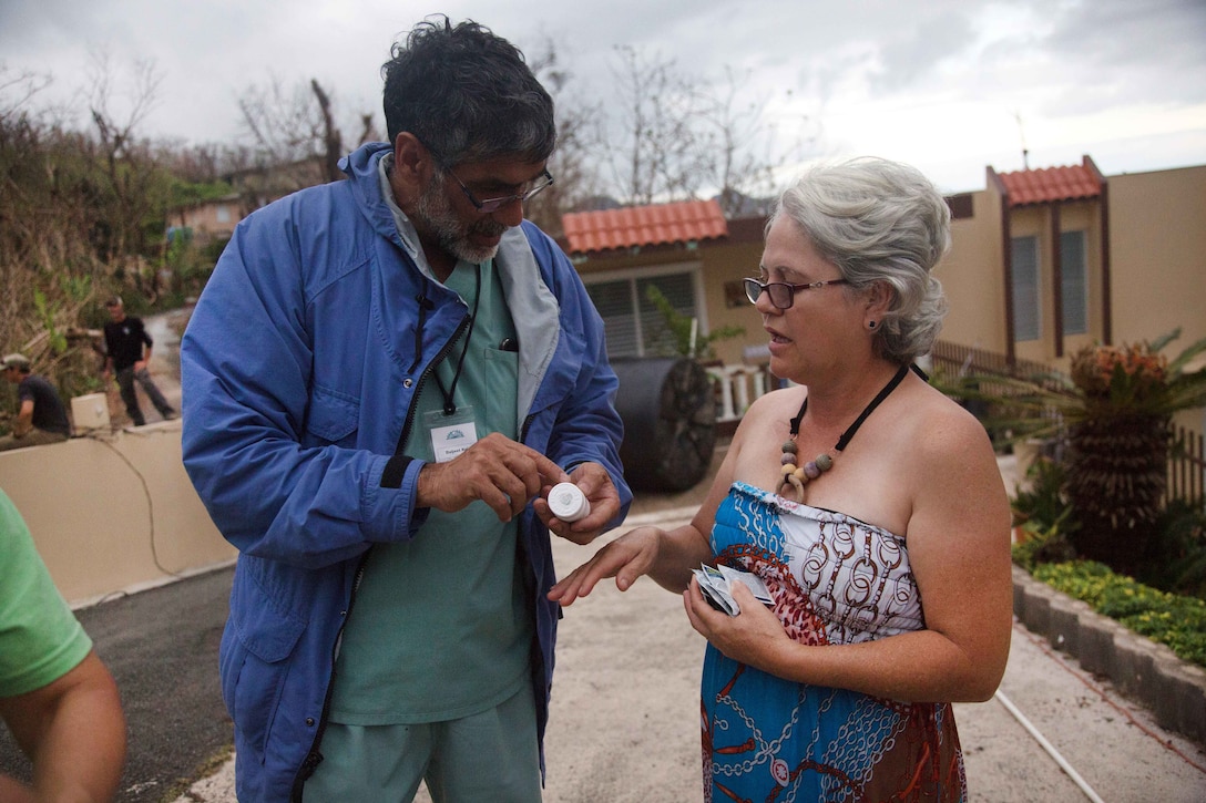 A doctor points to a label of a medicine bottle with a person nearby.