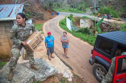 A soldier carries a box up steps.