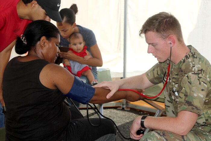 A soldier checks the blood pressure of a civilian.