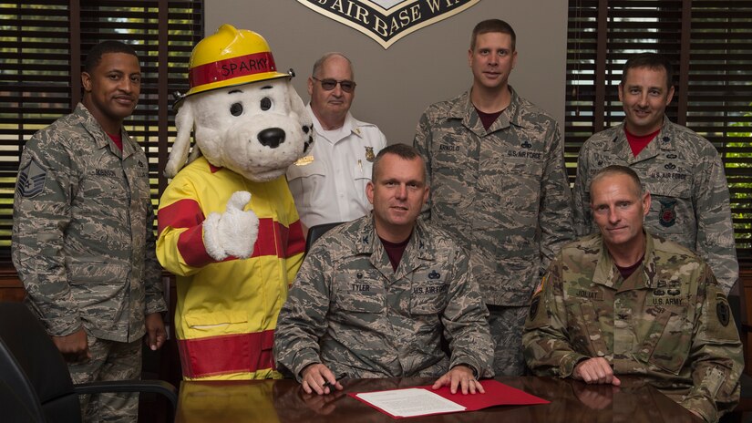 Center, U.S. Air Force Col. Sean Tyler, 633rd Air Base Wing commander, signs the Fire Prevention Week proclamation in the presence of senior leadership at Joint Base Langley-Eustis, Va., Oct. 6, 2017.