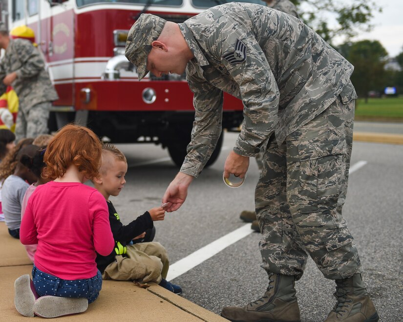 U.S. Air Force Staff Sgt. Corey Watkins, 633rd Civil Engineer Squadron firefighter crew chief, hands stickers to children from the Child Development Center at Joint Base Langley-Eustis, Va., Oct. 10, 2017.