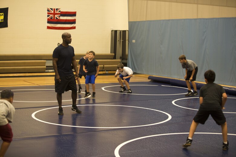 Retired Master Gunnery Sgt. Gus Alexander, the head coach of Marine Corps Base Hawaii’s youth wrestling team, leads wrestlers in warm-ups during a practice at the Youth Semper Fit Center, Oct. 12, 2017. The program, organized by Marine Corps Community Services, works in conjunction with Police Activities League and USA Wrestling to arrange wrestling tournaments with competitors from across the island of Oahu. (U.S. Marine Corps photo by Lance Cpl. Luke Kuennen)