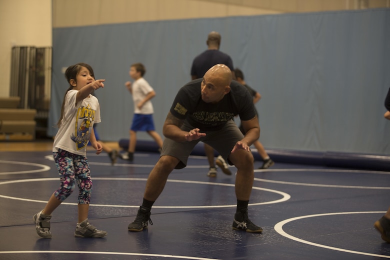 Chief Warrant Officer 3 Sergio Esquivel, an assistant wrestling coach of Marine Corps Base Hawaii’s youth wrestling team, works with his daughter during a wrestling practice at the Youth Semper Fit Center, Oct. 12, 2017. The program, organized by Marine Corps Community Services, works in conjunction with Police Activities League and USA Wrestling to arrange wrestling tournaments with competitors from across the island of Oahu. (U.S. Marine Corps photo by Lance Cpl. Luke Kuennen)