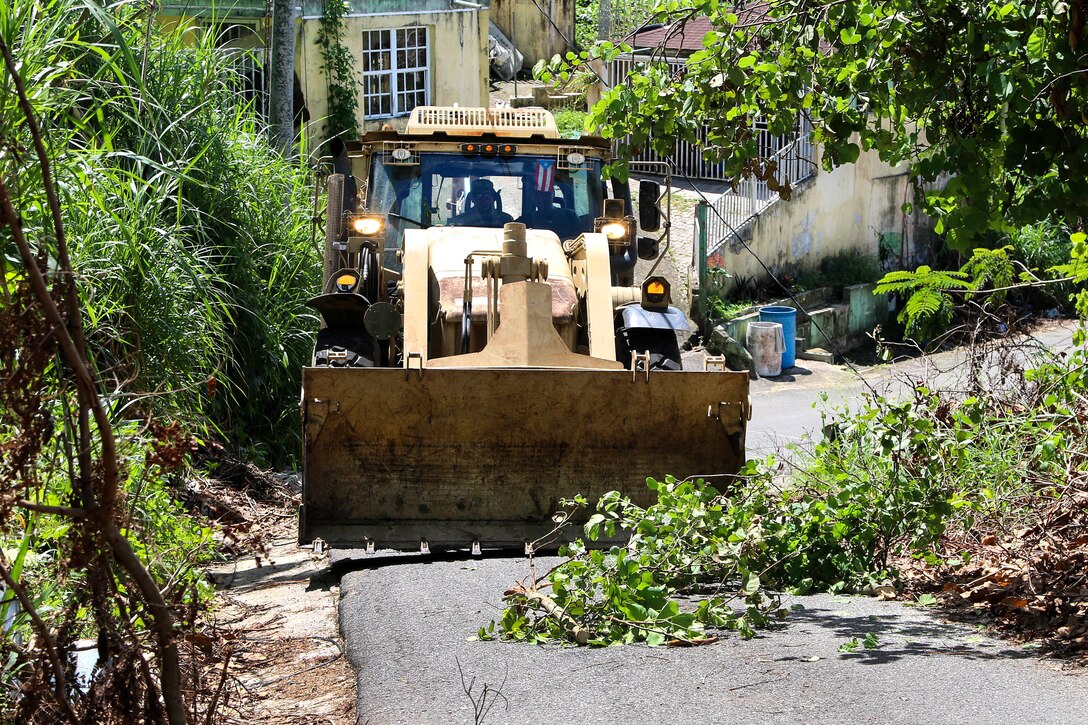 Army National Guardsmen operate a bulldozer clearing debris from the roads.